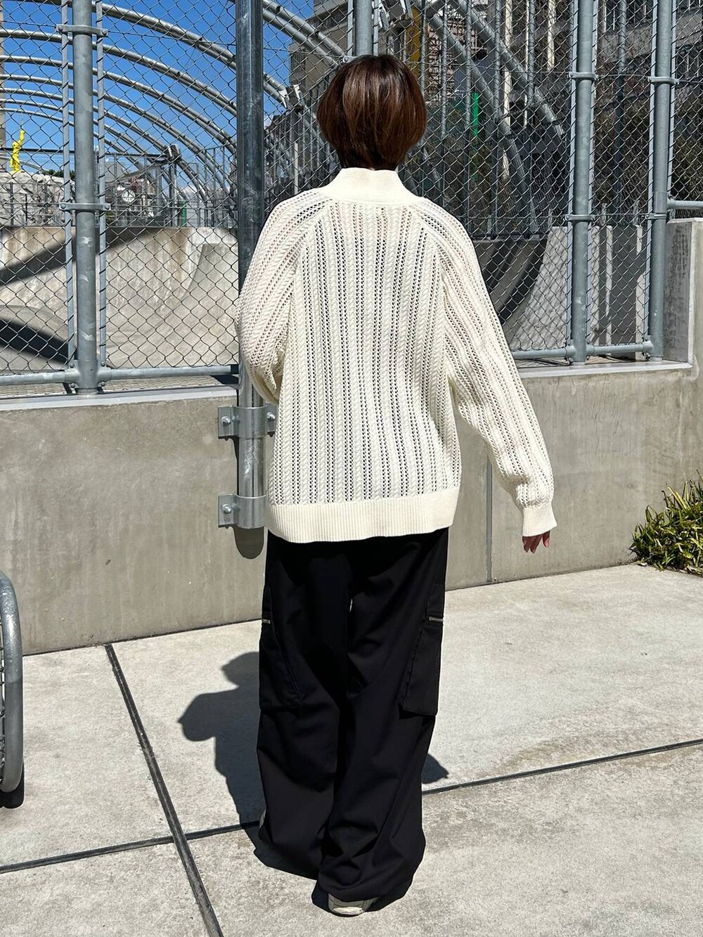 グレー系のタンクトップ、ホワイト系のカーディガン/ボレロ、ブラック系のスラックスを着用したレディースの春コーディネートの5枚目の写真