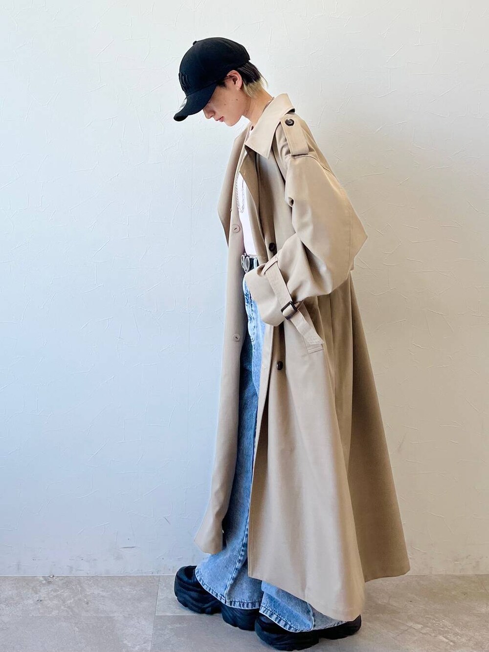 ブラック系のスニーカー、ベージュ系のトレンチコート、ブルー系のデニムパンツを着用したレディースの春コーディネートの4枚目の写真