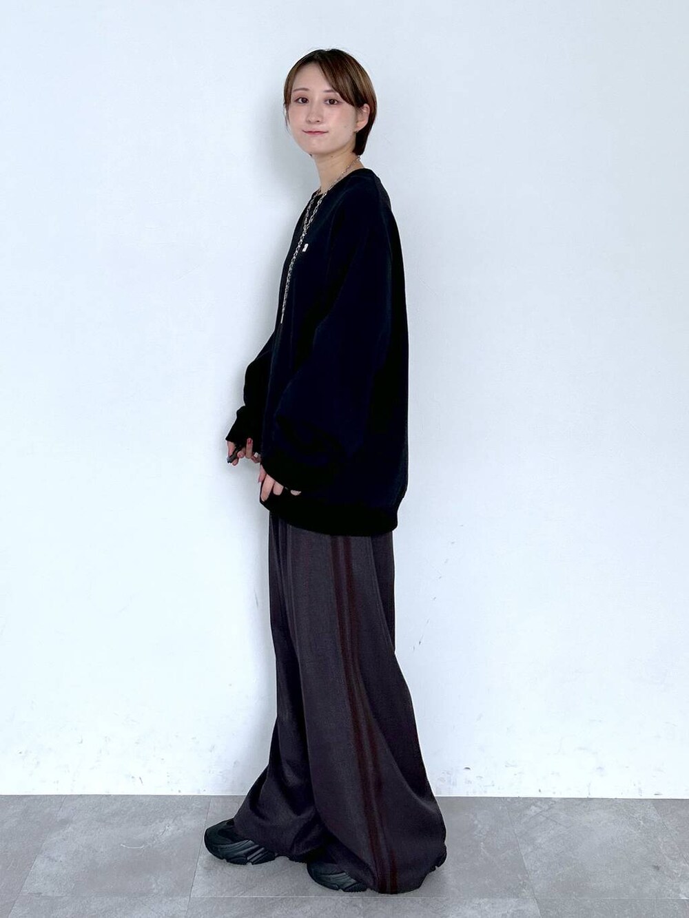 ブラウン系のスラックス、ブラック系のスウェット、シルバー系のピアス（両耳用）を着用したレディースの夏コーディネートの5枚目の写真