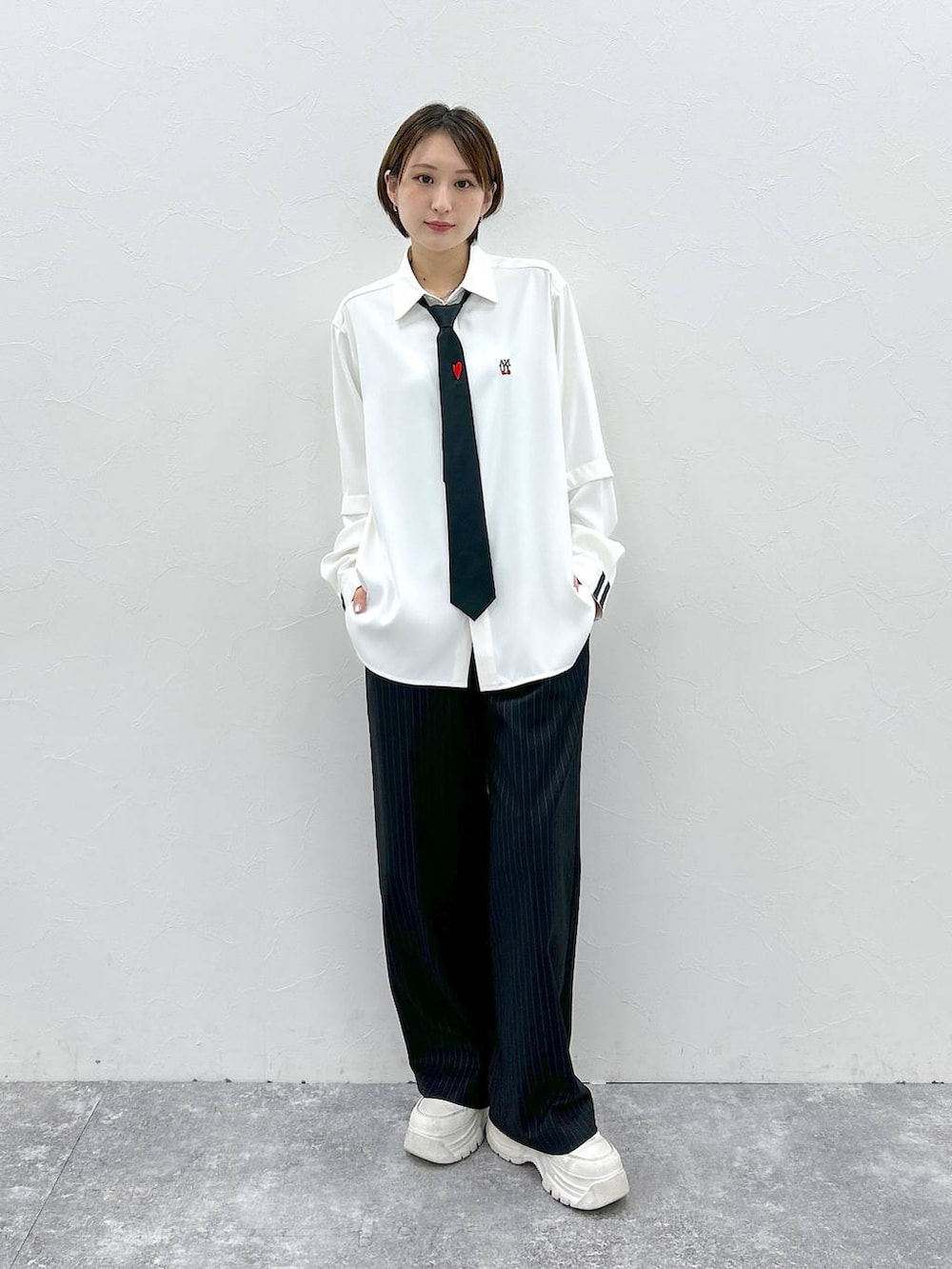 ブラック系のネクタイ、ホワイト系のシャツ/ブラウス、ブラック系のスラックスを着用したレディースの春コーディネートの3枚目の写真