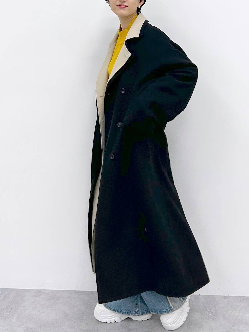 イエロー系のニット/セーター、ブルー系のデニムパンツ、ブラック系のその他アウターを着用したレディースの秋コーディネートの4枚目の写真