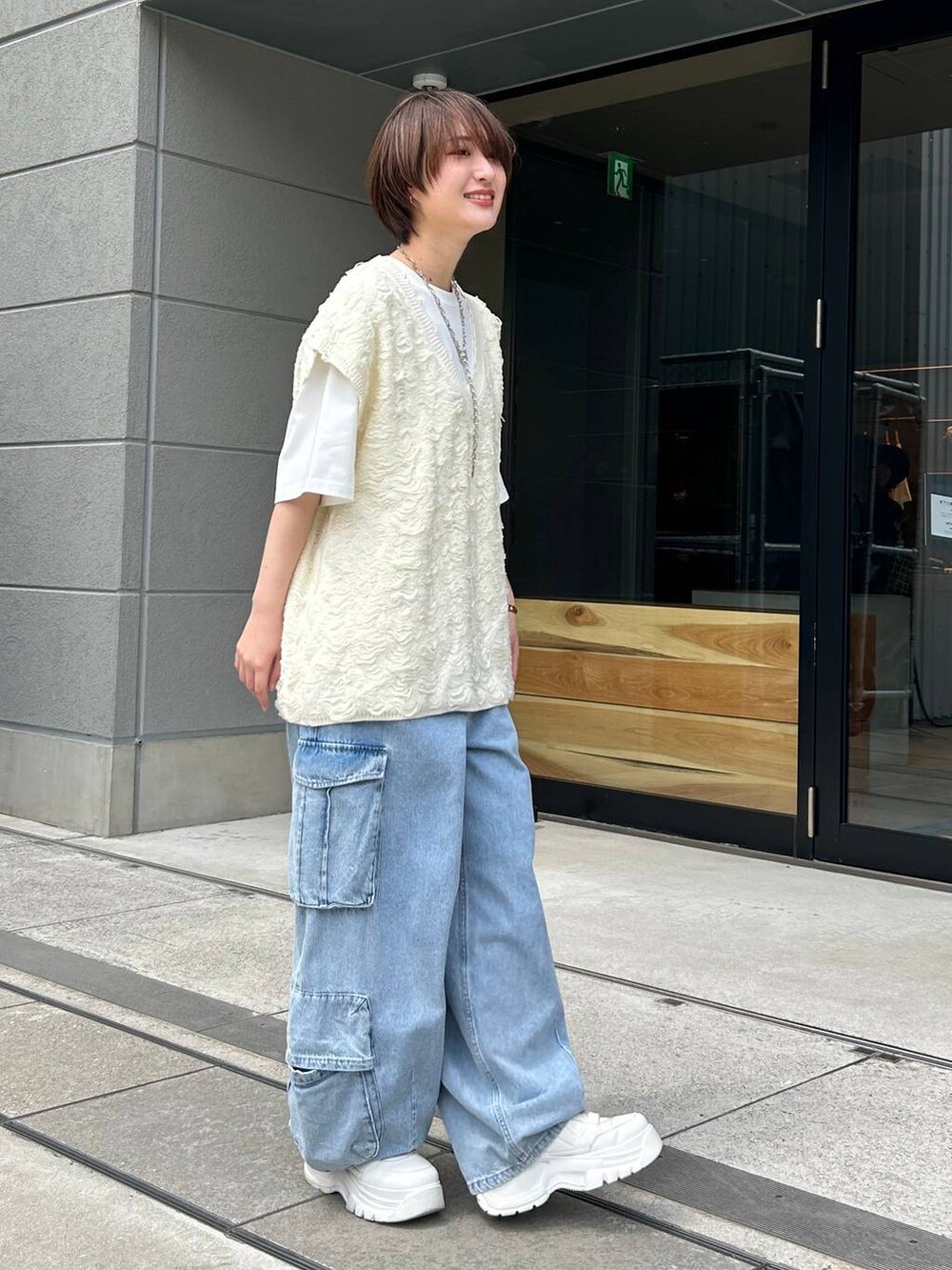 ホワイト系のベスト、ホワイト系のTシャツ/カットソー、ブルー系のデニムパンツを着用したレディースの夏コーディネートの5枚目の写真