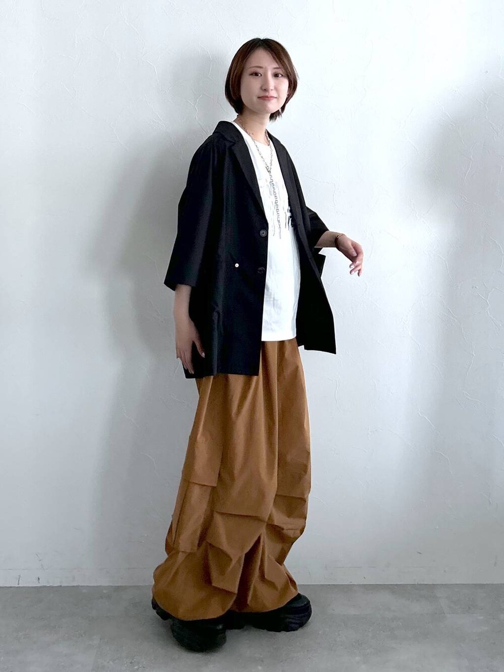 ブラック系のテーラードジャケット、ブラウン系のカーゴパンツ、ホワイト系のTシャツ/カットソーを着用したレディースの春コーディネートの4枚目の写真
