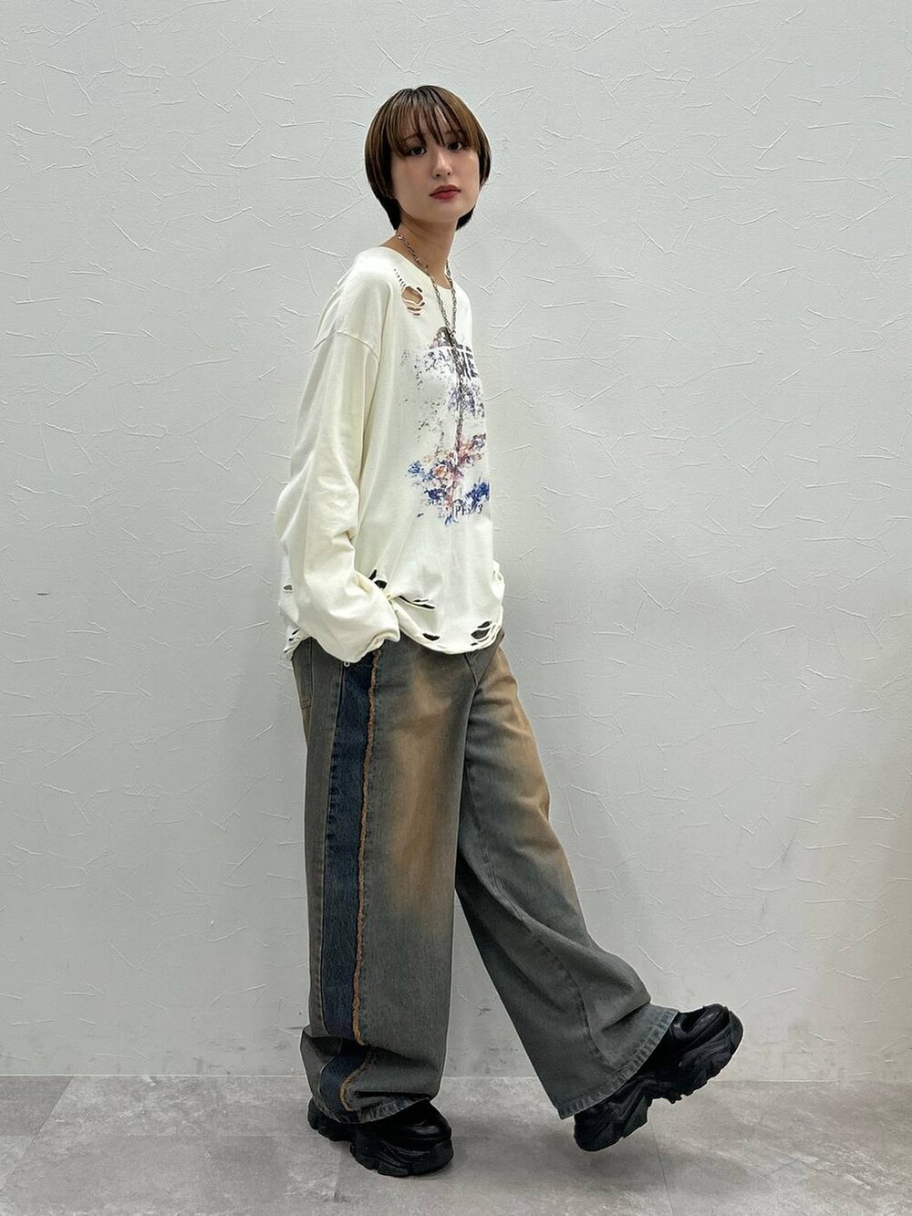 ブラック系のスニーカー、ホワイト系のTシャツ/カットソー、ブルー系のデニムパンツを着用したレディースの秋コーディネートの3枚目の写真