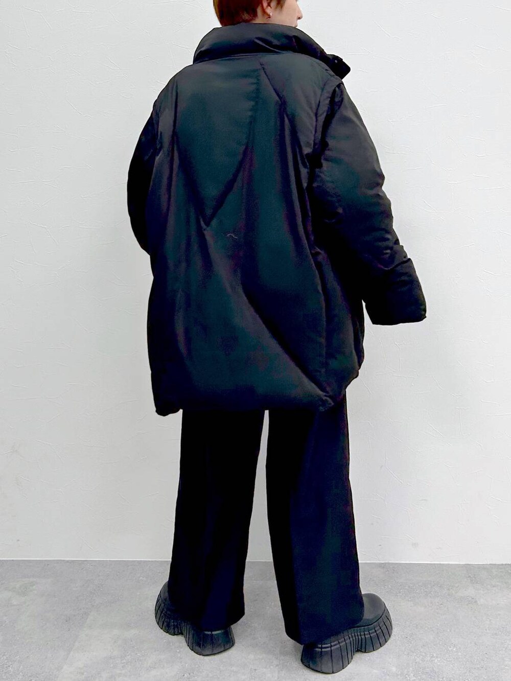 ブラック系のブルゾン、レッド系のニット/セーター、ブラック系のスラックスを着用したレディースの冬コーディネートの8枚目の写真