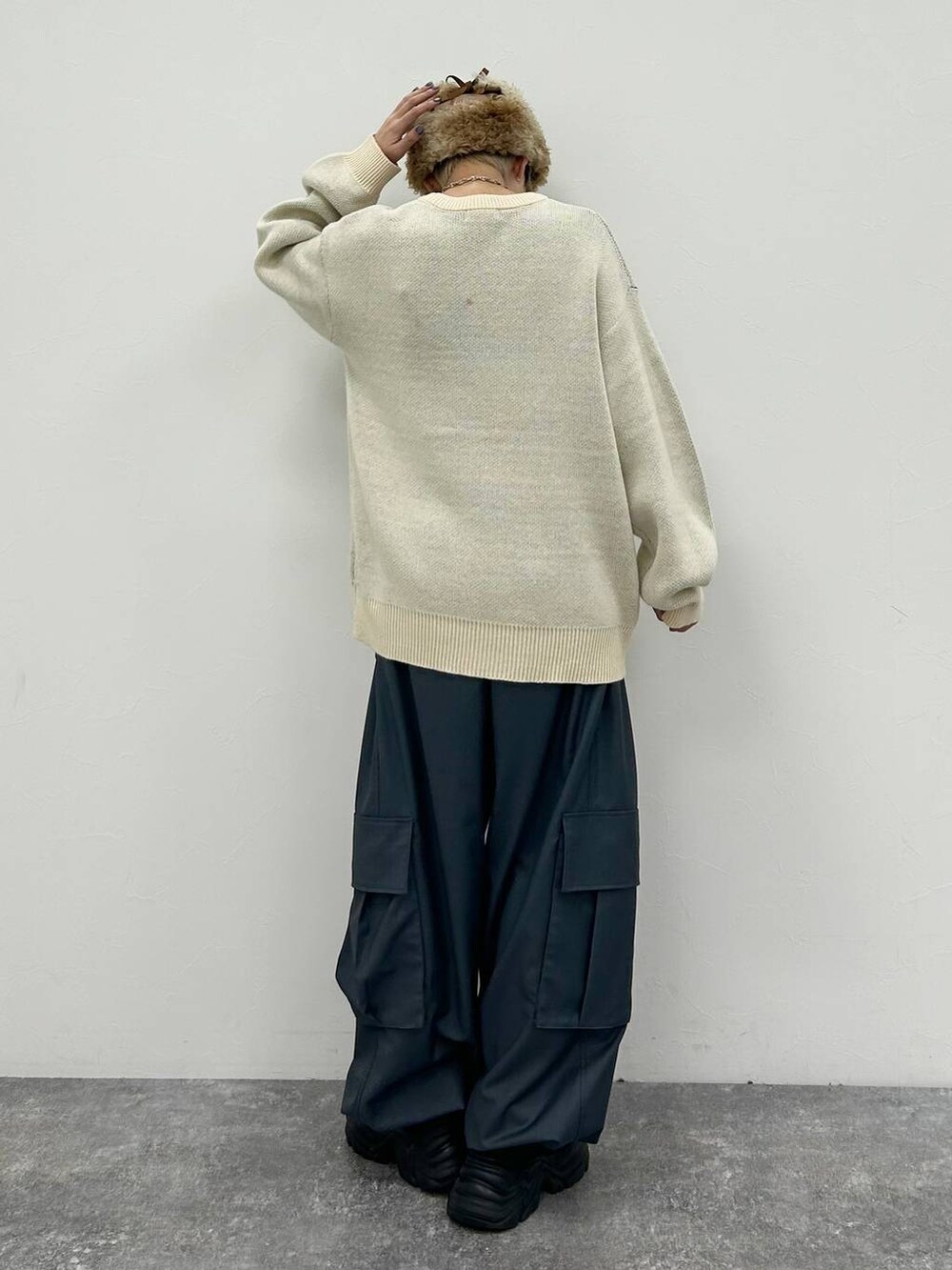 ブラック系のスニーカー、ホワイト系のニット/セーター、グレー系のカーゴパンツを着用したレディースの冬コーディネートの6枚目の写真