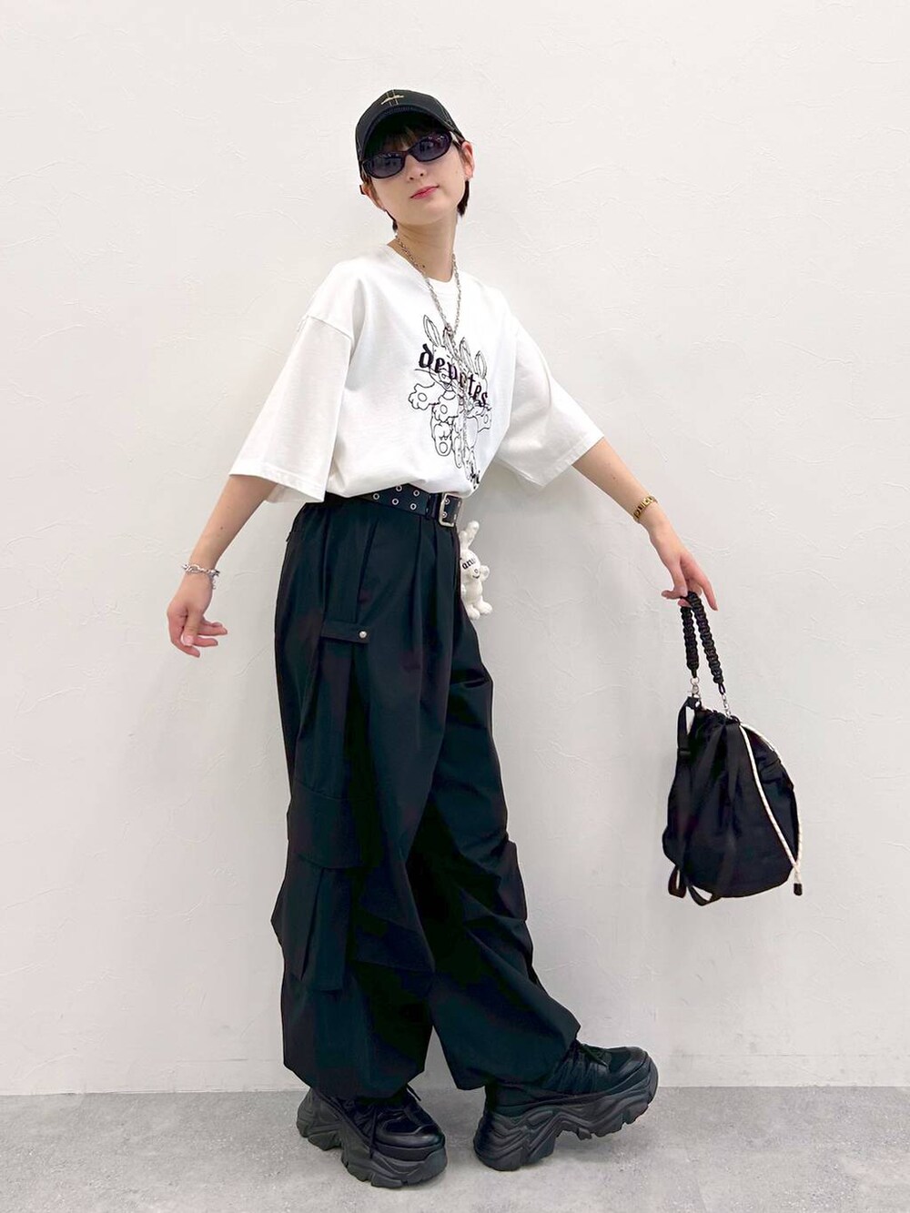 ブラック系のスニーカー、ホワイト系のTシャツ/カットソー、ブラック系のショルダーバッグを着用したレディースの夏コーディネートの6枚目の写真