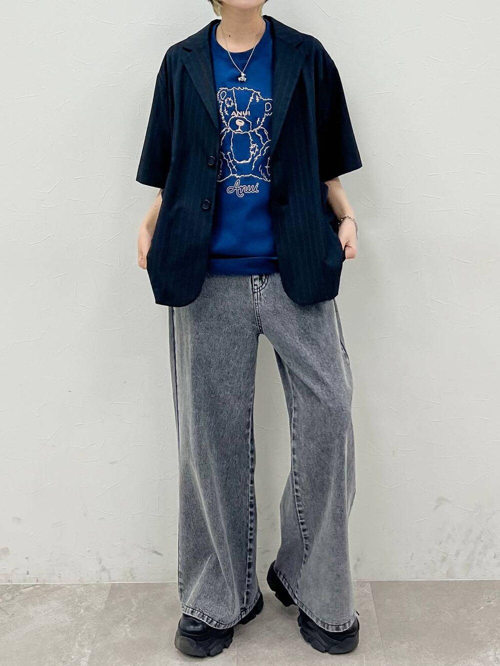 ブラック系のスニーカー、ブルー系のTシャツ/カットソー、ブラック系のデニムパンツを着用したレディースの春コーディネートの2枚目の写真