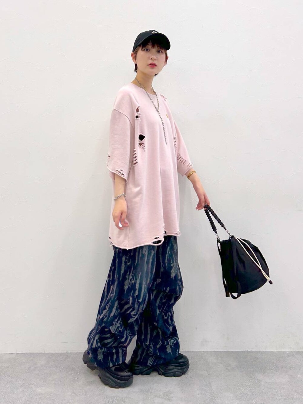 ブラック系のスニーカー、ブラック系のショルダーバッグ、ピンク系のTシャツ/カットソーを着用したレディースの夏コーディネートの6枚目の写真