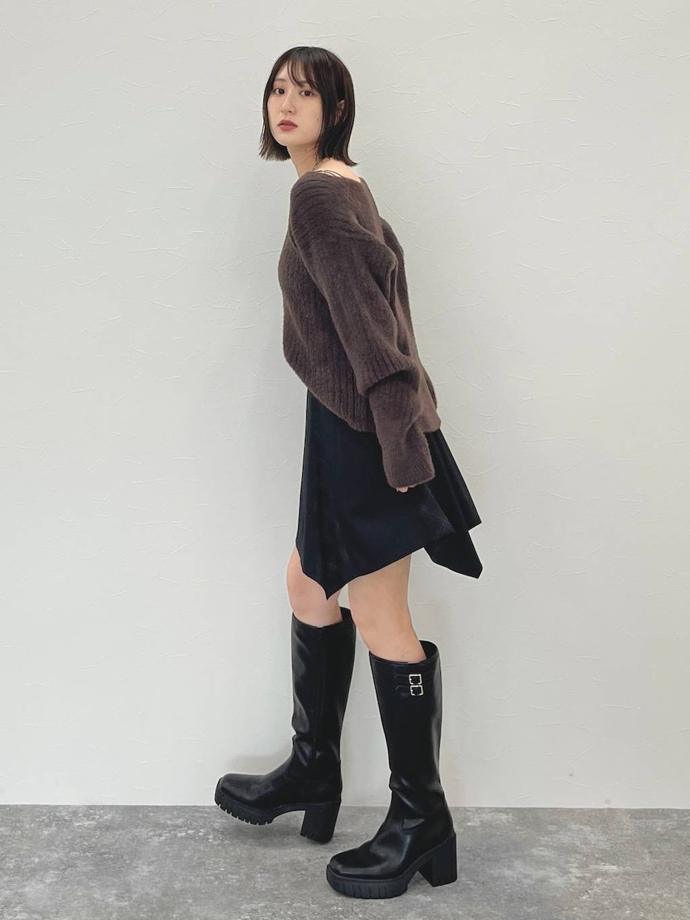 ブラック系のスカート、ブラウン系のニット/セーターを着用したレディースの秋コーディネートの4枚目の写真