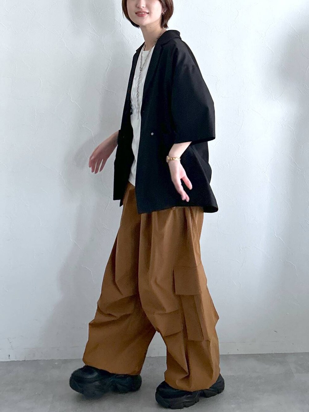 ブラック系のテーラードジャケット、ブラウン系のカーゴパンツ、ホワイト系のTシャツ/カットソーを着用したレディースの春コーディネートの5枚目の写真