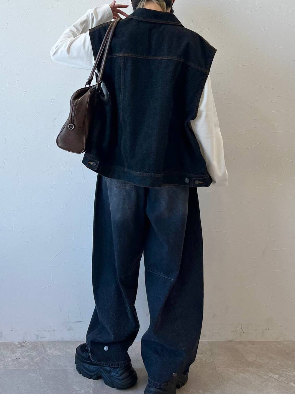 ブラック系のスニーカー、ブラック系のデニムパンツ、ブラウン系のボストンバッグを着用したレディースの春コーディネートの9枚目の写真