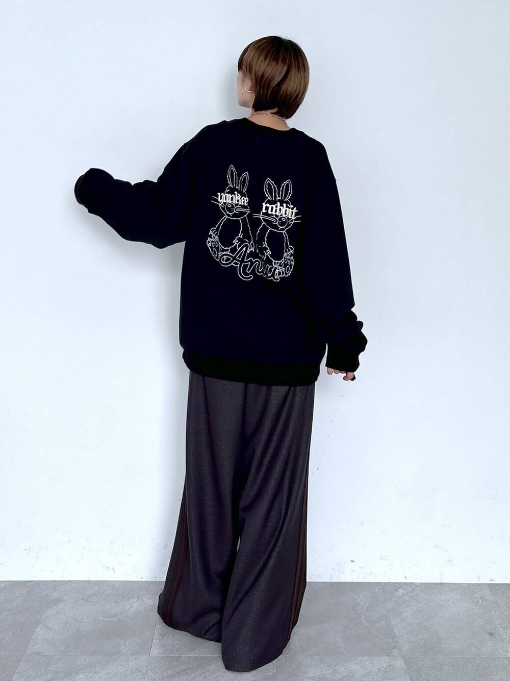 ブラウン系のスラックス、ブラック系のスウェット、シルバー系のピアス（両耳用）を着用したレディースの夏コーディネートの3枚目の写真