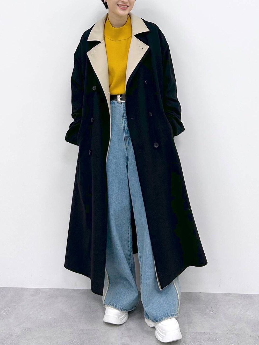 イエロー系のニット/セーター、ブルー系のデニムパンツ、ブラック系のその他アウターを着用したレディースの秋コーディネートの2枚目の写真