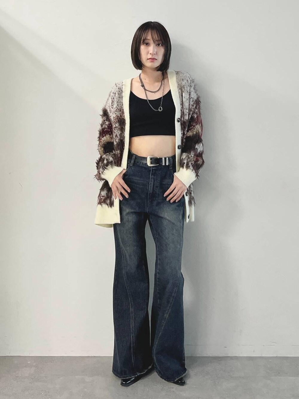 ブルー系のデニムパンツ、ブラック系のパンプス、ホワイト系のカーディガン/ボレロを着用したレディースの秋コーディネートの3枚目の写真