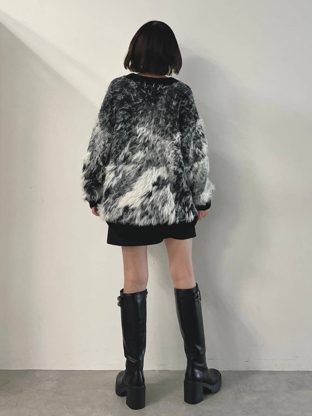 ブラック系のキャミソール、ブラック系のブーツ、ブラック系のスカートを着用したレディースの秋コーディネートの4枚目の写真