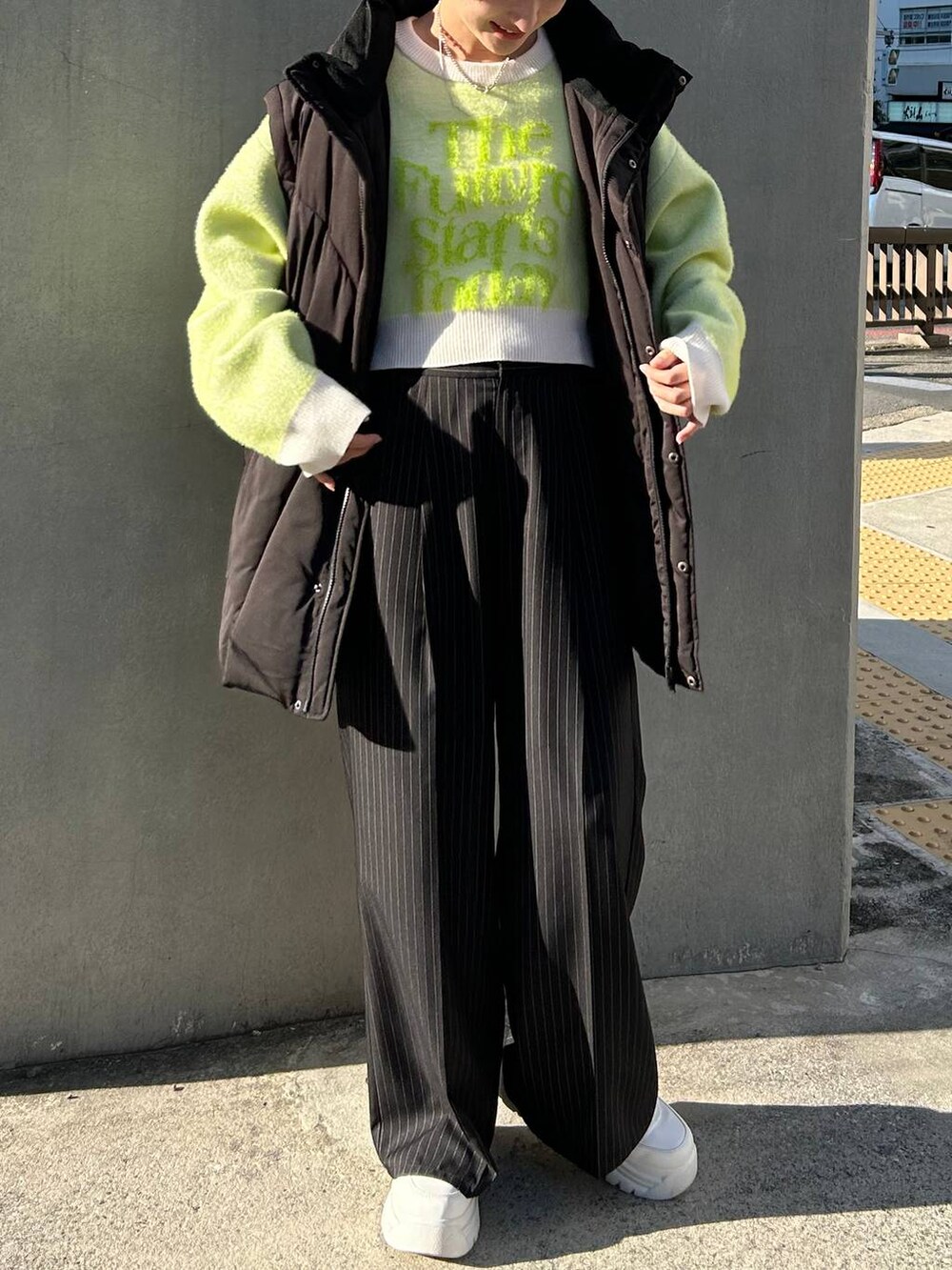 ブラック系のスラックス、ホワイト系のニット/セーター、ブラック系のブルゾンを着用したレディースの冬コーディネートの3枚目の写真