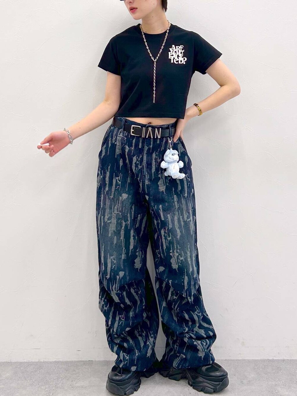 ブラック系のスニーカー、ブラック系のTシャツ/カットソー、ブルー系のデニムパンツを着用したレディースの夏コーディネートの3枚目の写真