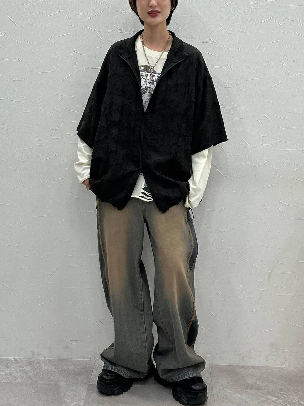 ブラック系のスニーカー、ホワイト系のTシャツ/カットソー、ブルー系のデニムパンツを着用したレディースの秋コーディネートの2枚目の写真