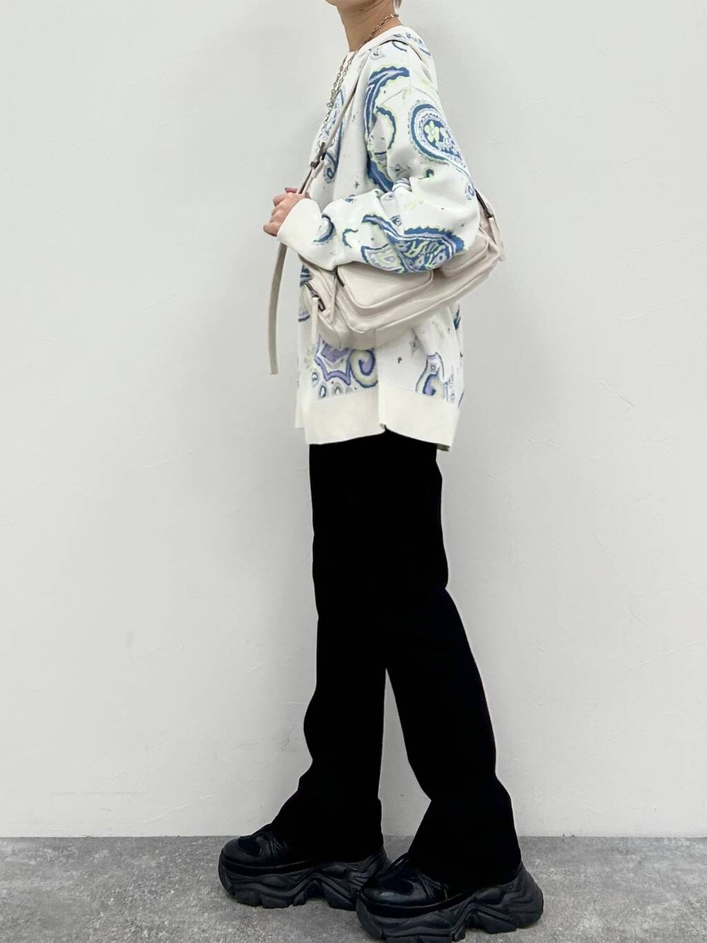 ブラック系のスニーカー、ホワイト系のショルダーバッグ、ブラック系のデニムパンツを着用したレディースの冬コーディネートの4枚目の写真