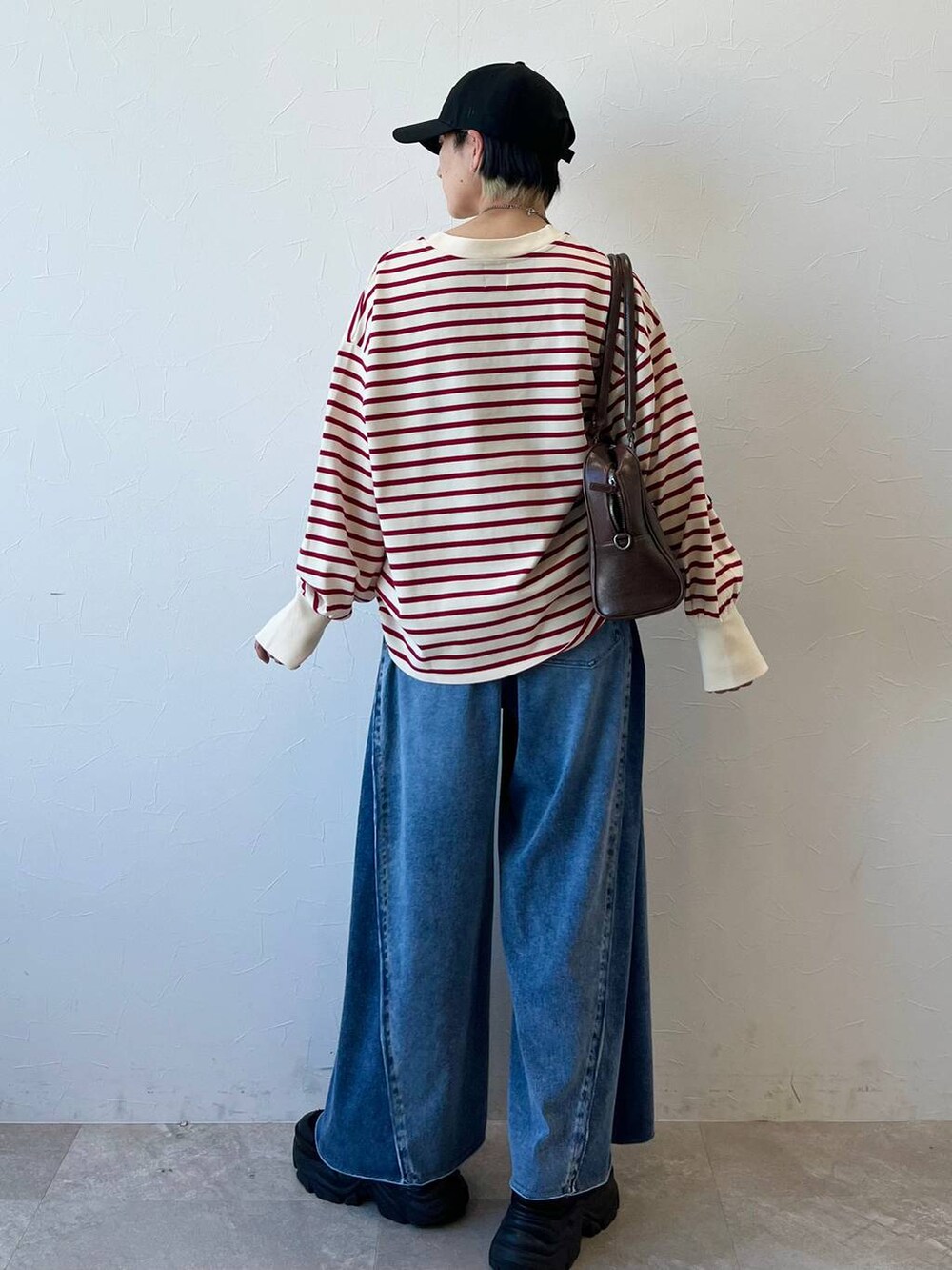 ブラック系のスニーカー、ブラウン系のボストンバッグ、ブルー系のデニムパンツを着用したレディースの春コーディネートの6枚目の写真