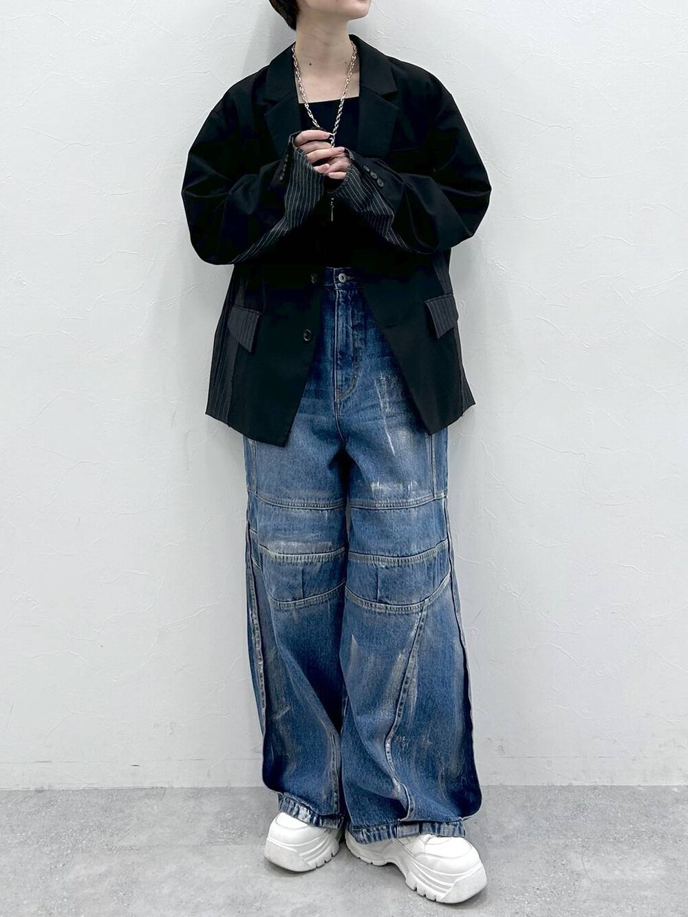 ブラック系のテーラードジャケット、ブルー系のデニムパンツ、シルバー系のネックレスを着用したレディースの春コーディネートの2枚目の写真