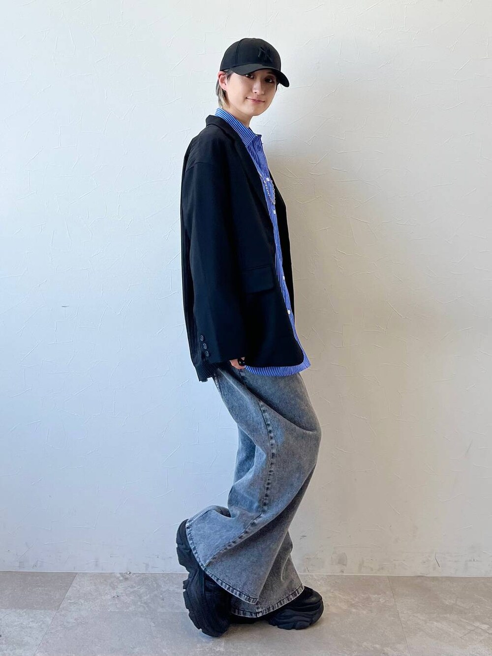 ブラック系のスニーカー、ブラック系のテーラードジャケット、ブラック系のデニムパンツを着用したレディースの春コーディネートの3枚目の写真