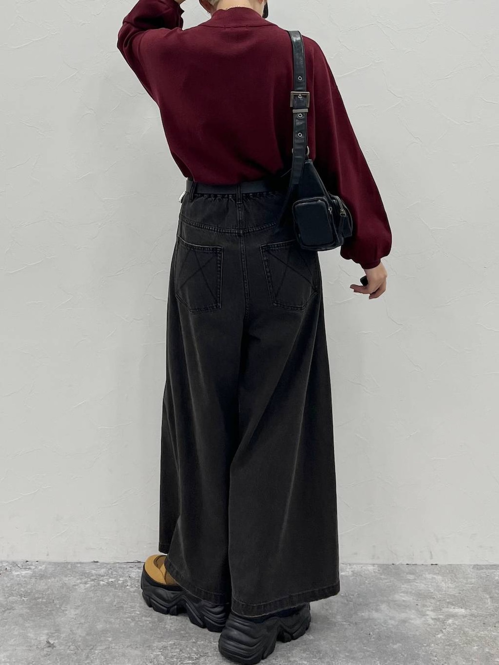 ブラック系のデニムパンツ、ブラウン系のブーツ、レッド系のニット/セーターを着用したレディースの秋コーディネートの7枚目の写真