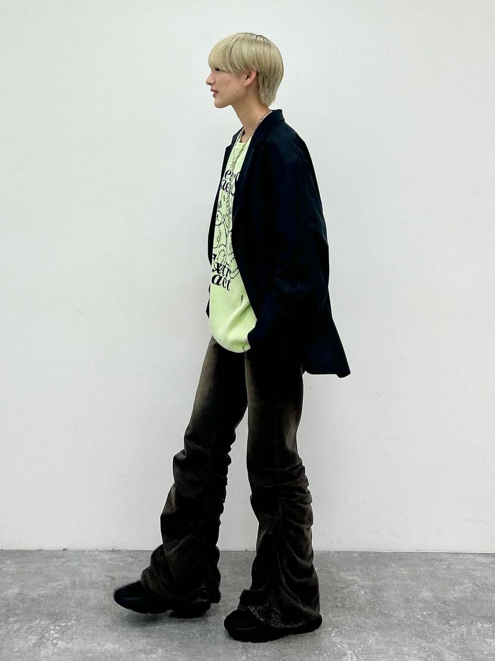 ブラック系のデニムパンツ、ブラック系のテーラードジャケット、グリーン系のニット/セーターを着用したレディースの秋コーディネートの3枚目の写真