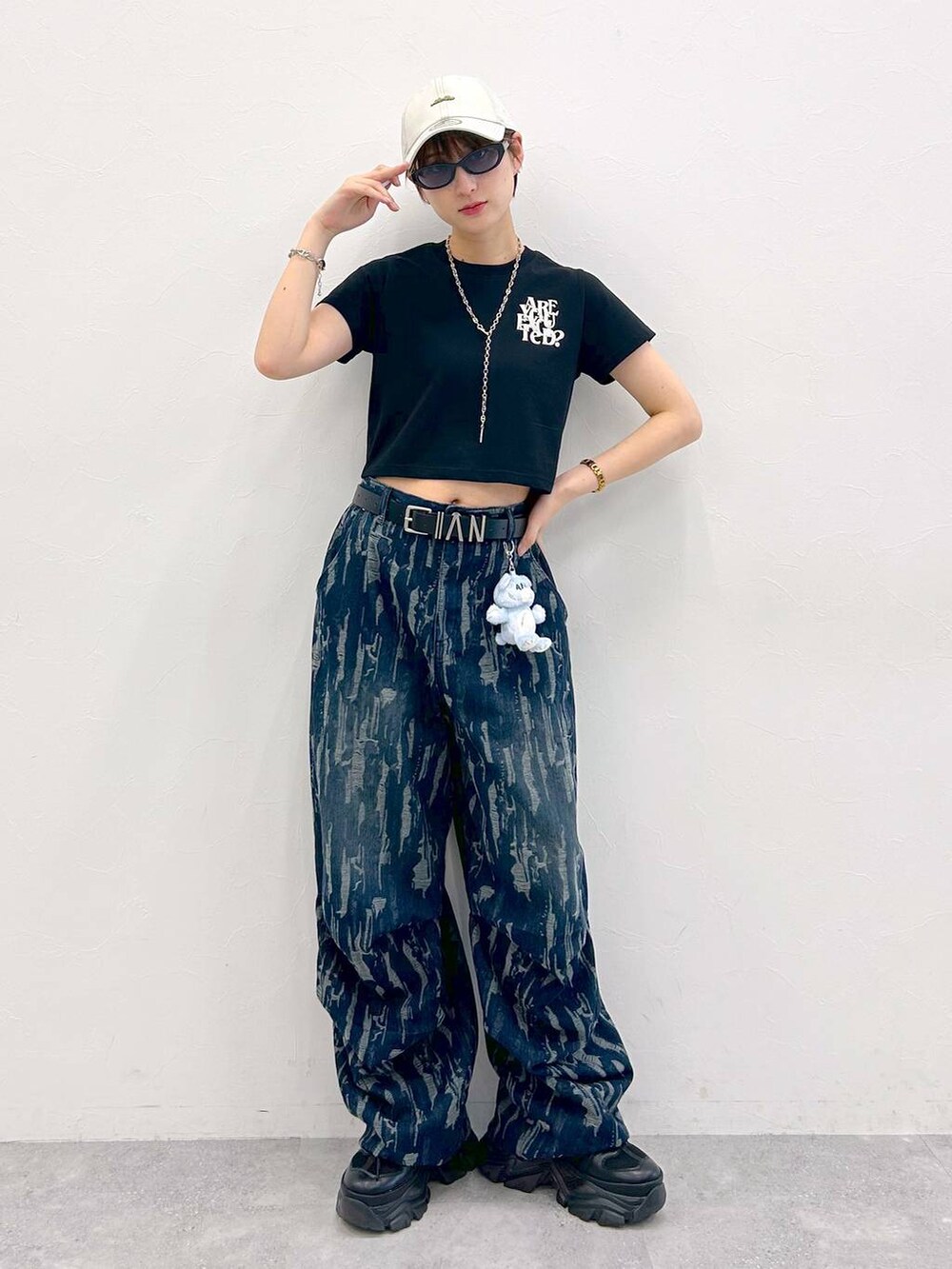 ブラック系のスニーカー、ブラック系のTシャツ/カットソー、ブルー系のデニムパンツを着用したレディースの夏コーディネートの2枚目の写真