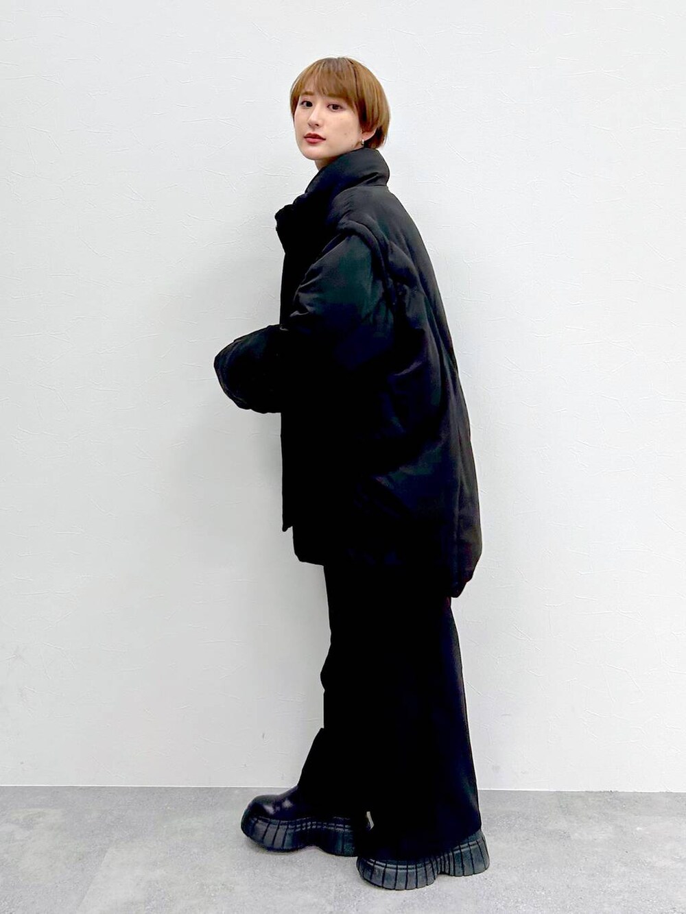 ブラック系のブルゾン、レッド系のニット/セーター、ブラック系のスラックスを着用したレディースの冬コーディネートの3枚目の写真