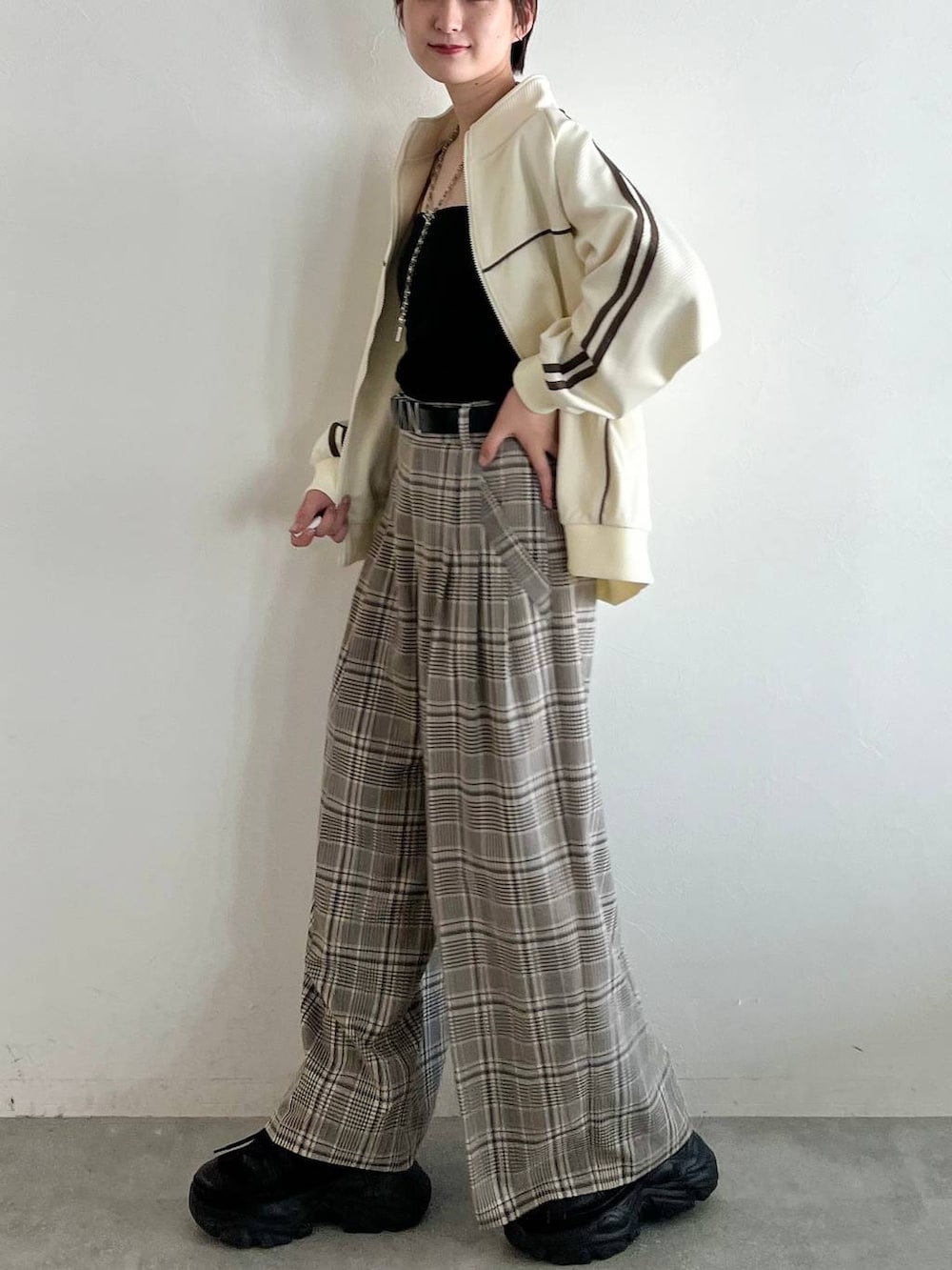 ブラック系のスニーカー、ベージュ系のスラックス、ホワイト系のジャージを着用したレディースの秋コーディネートの5枚目の写真