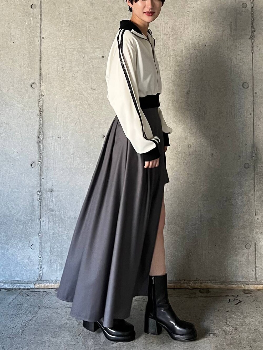 ブラック系のキャミソール、ブラック系のブーツ、グレー系のスカートを着用したレディースの冬コーディネートの5枚目の写真
