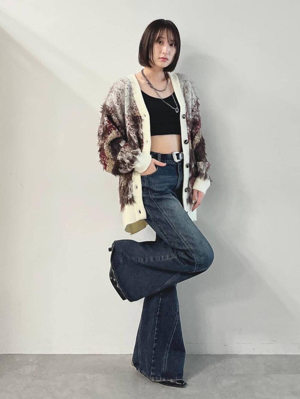 ブルー系のデニムパンツ、ブラック系のパンプス、ホワイト系のカーディガン/ボレロを着用したレディースの秋コーディネートの2枚目の写真