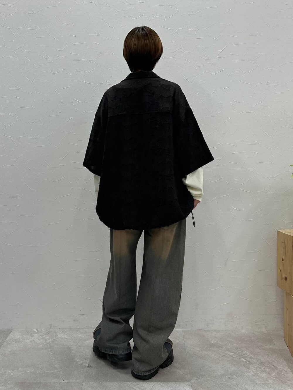 ブラック系のスニーカー、ホワイト系のTシャツ/カットソー、ブルー系のデニムパンツを着用したレディースの秋コーディネートの7枚目の写真