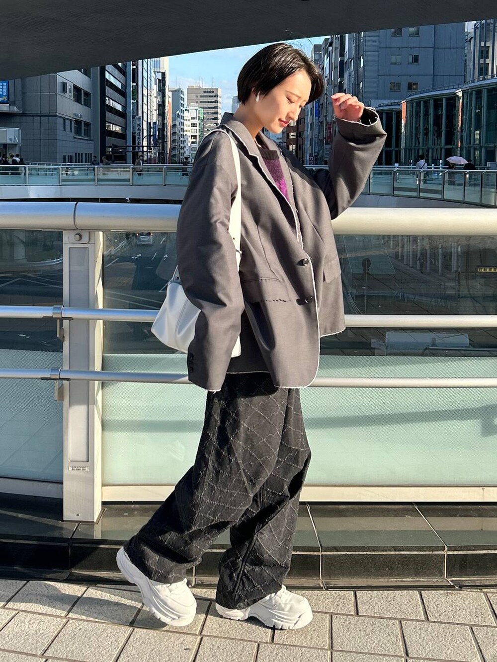 グレー系のテーラードジャケット、ブラック系のニット/セーター、ブラック系のデニムパンツを着用したレディースの冬コーディネートの3枚目の写真