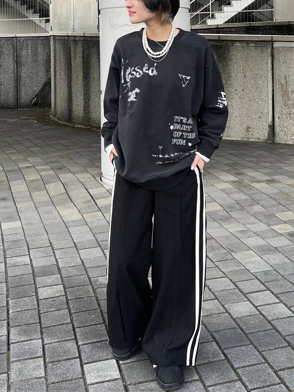 グレー系のスウェット、ブラック系のスラックス、ベージュ系のネックレスを着用したレディースの春コーディネートの2枚目の写真