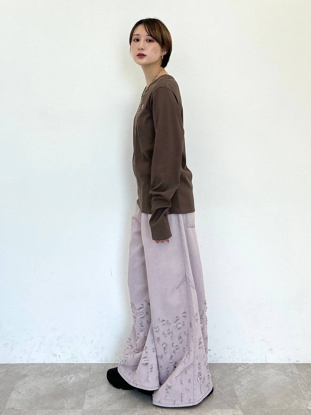 ピンク系のデニムパンツ、ブラウン系のTシャツ/カットソー、シルバー系のネックレスを着用したレディースの秋コーディネートの3枚目の写真