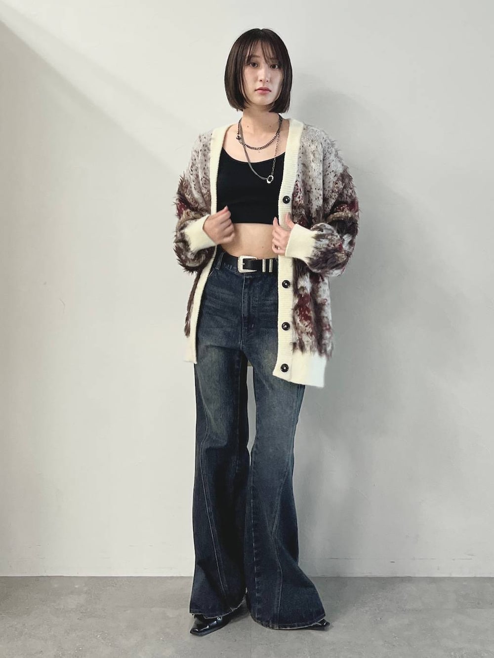 ブルー系のデニムパンツ、ブラック系のパンプス、ホワイト系のカーディガン/ボレロを着用したレディースの秋コーディネートの4枚目の写真