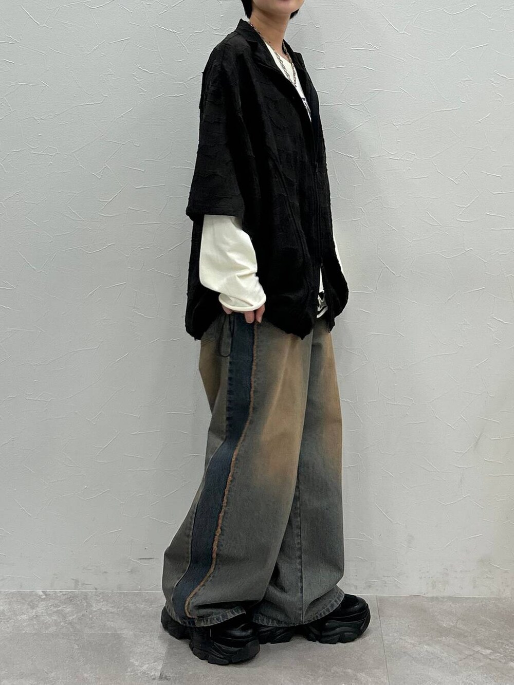 ブラック系のスニーカー、ホワイト系のTシャツ/カットソー、ブルー系のデニムパンツを着用したレディースの秋コーディネートの6枚目の写真