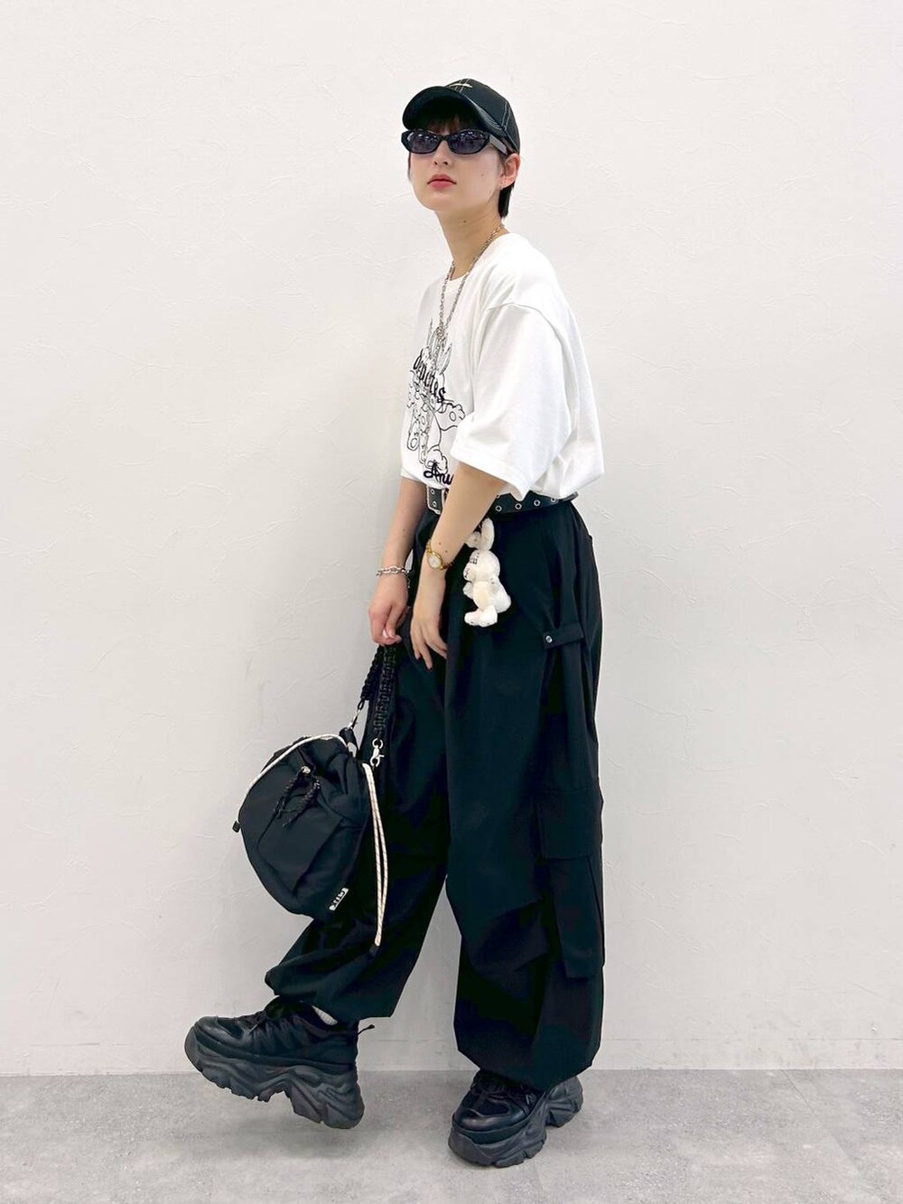 ブラック系のスニーカー、ホワイト系のTシャツ/カットソー、ブラック系のショルダーバッグを着用したレディースの夏コーディネートの4枚目の写真