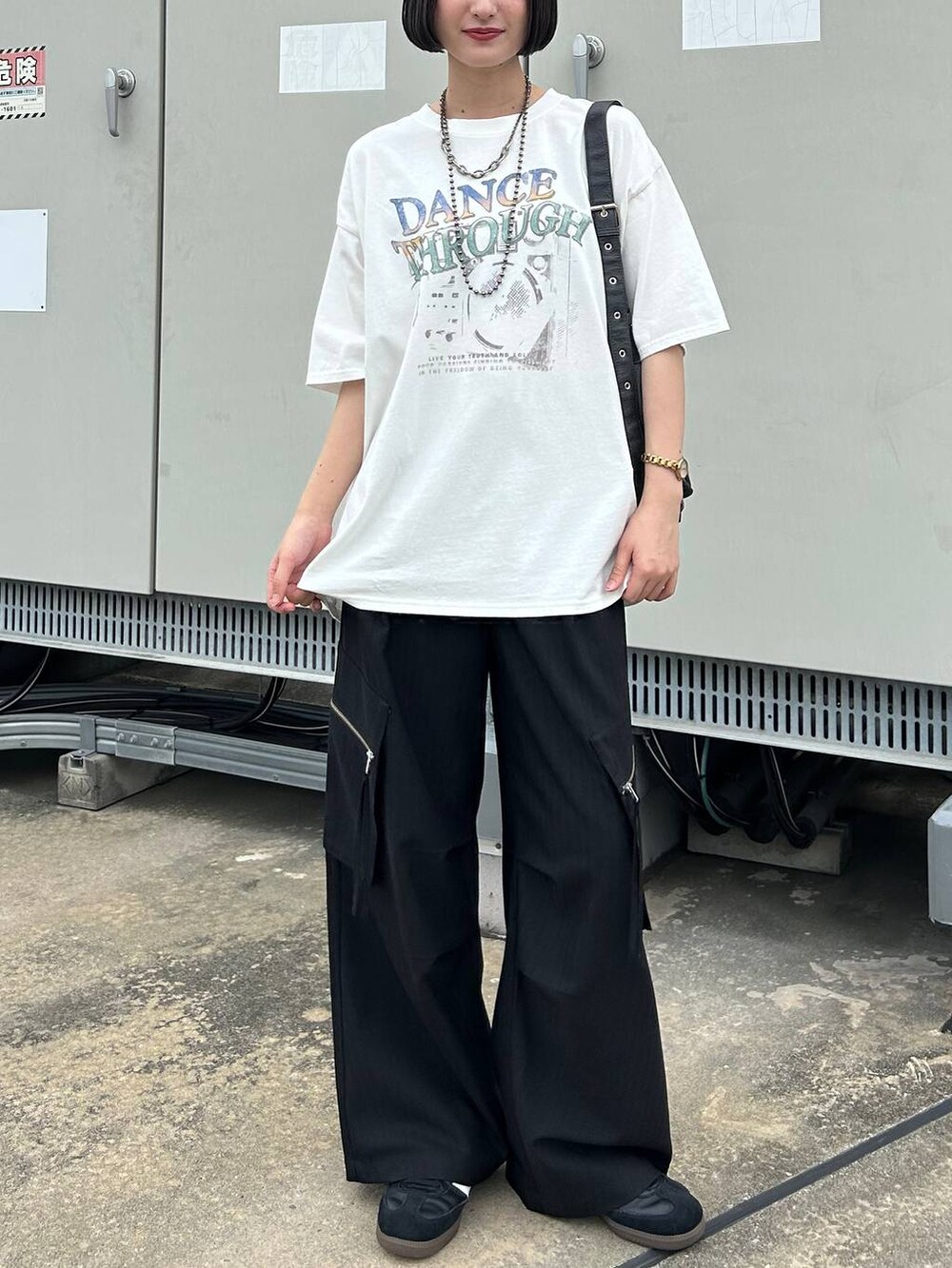 ブラック系のカーゴパンツ、ブラック系のショルダーバッグ、ホワイト系のTシャツ/カットソーを着用したレディースの夏コーディネートの2枚目の写真
