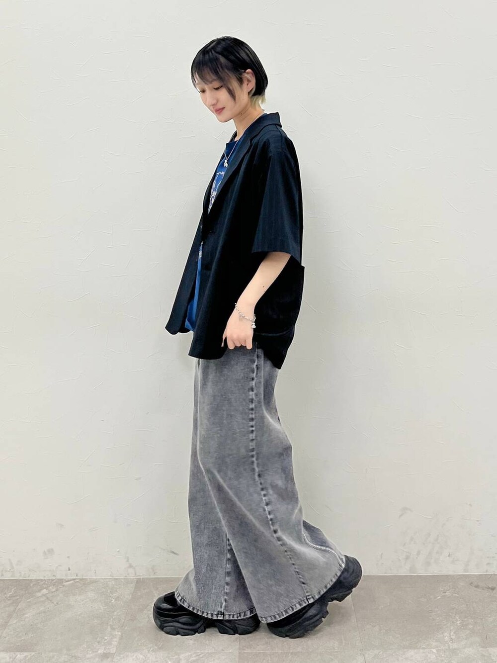 ブラック系のスニーカー、ブルー系のTシャツ/カットソー、ブラック系のデニムパンツを着用したレディースの春コーディネートの3枚目の写真