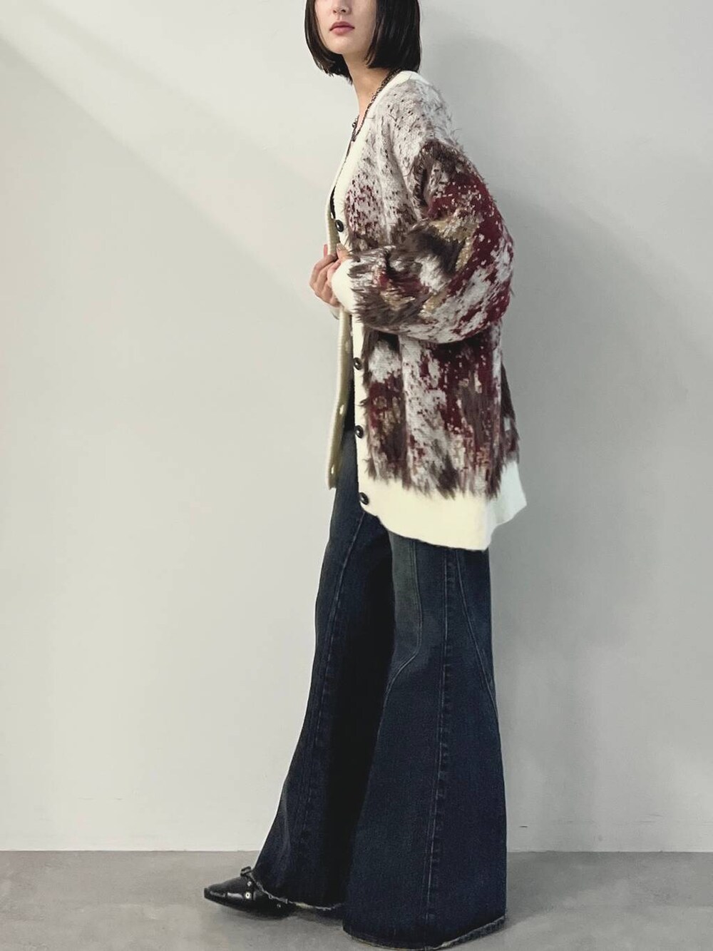 ブルー系のデニムパンツ、ブラック系のパンプス、ホワイト系のカーディガン/ボレロを着用したレディースの秋コーディネートの6枚目の写真