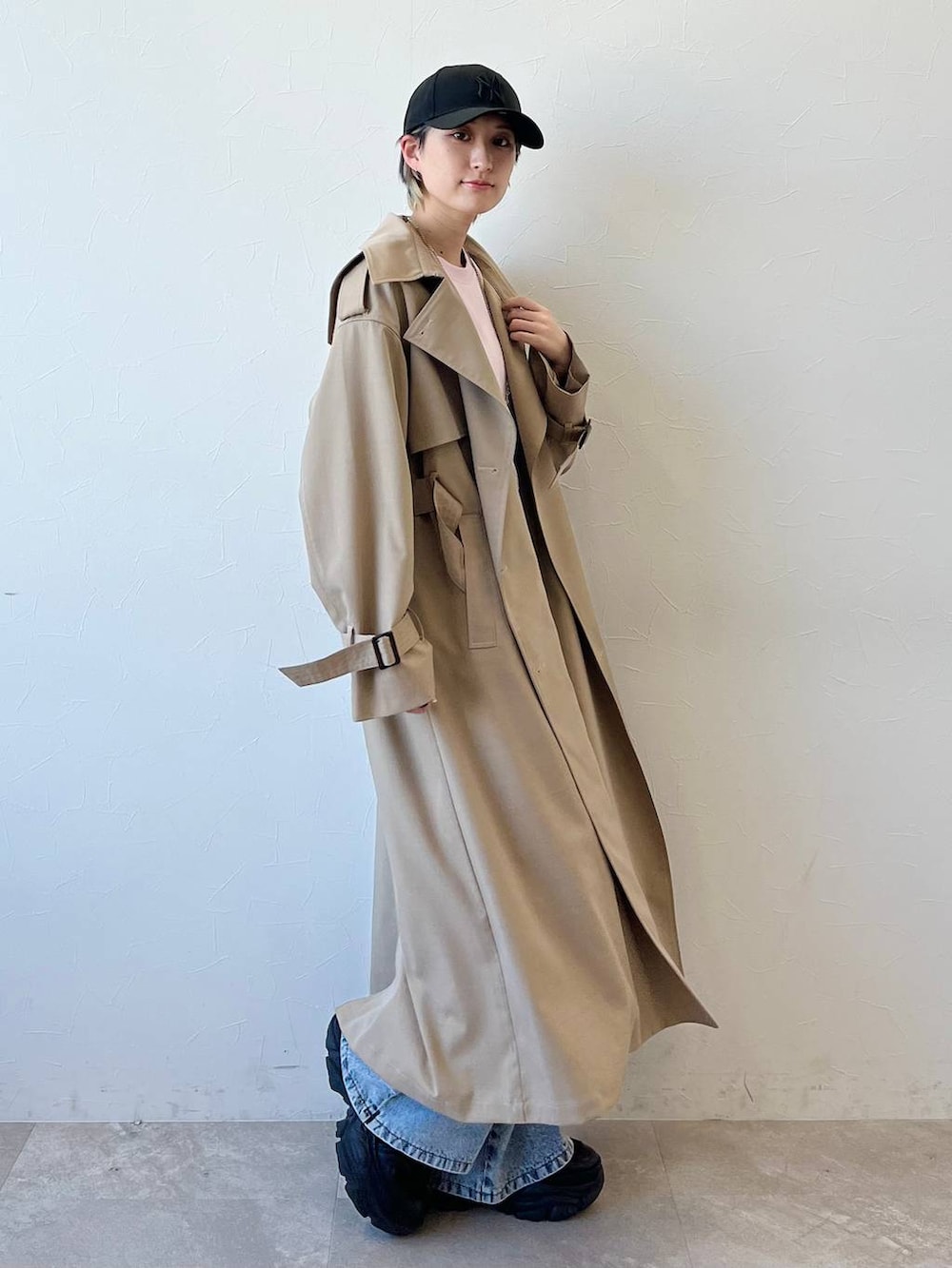 ブラック系のスニーカー、ベージュ系のトレンチコート、ブルー系のデニムパンツを着用したレディースの春コーディネートの2枚目の写真