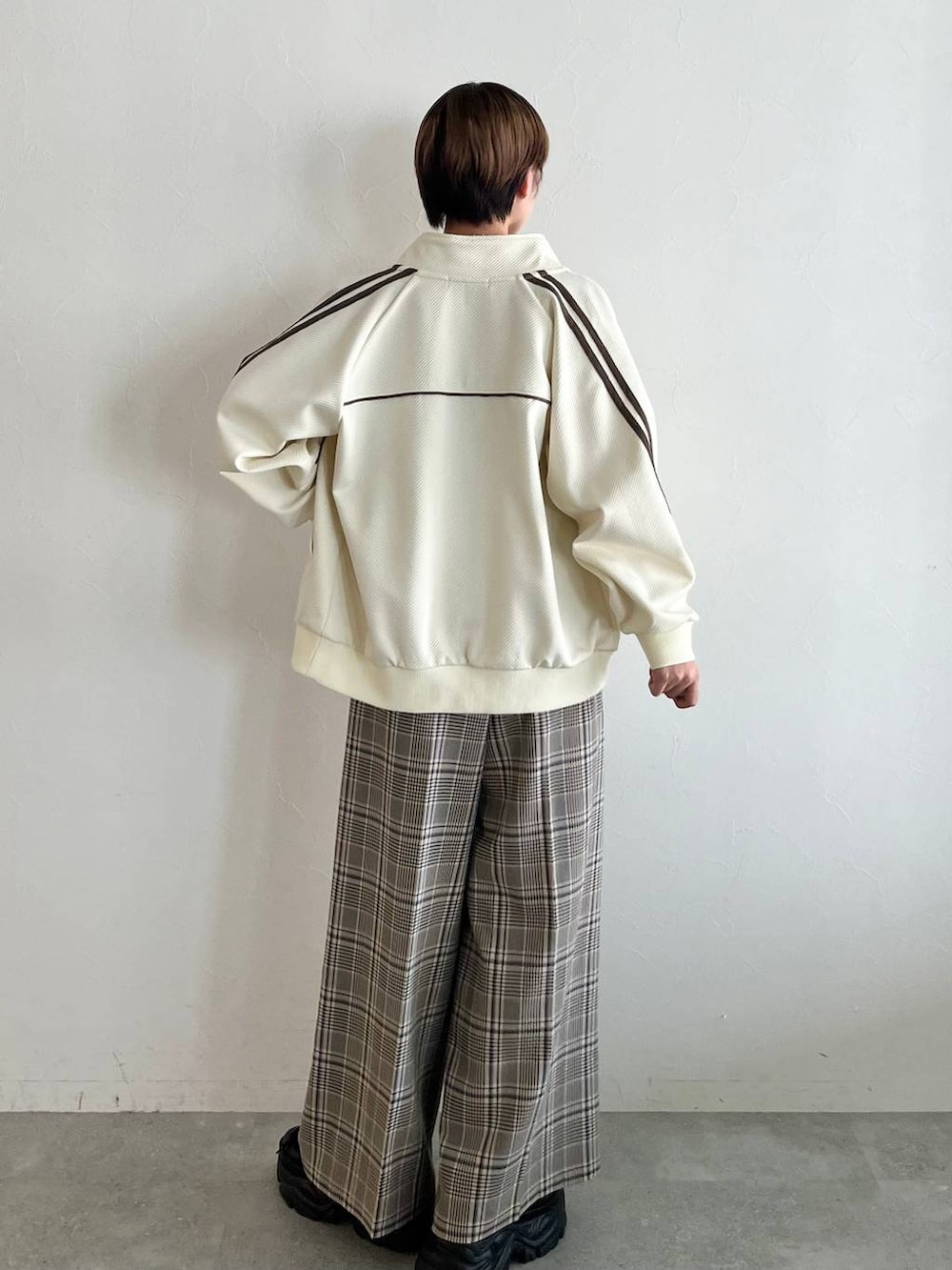 ブラック系のスニーカー、ベージュ系のスラックス、ホワイト系のジャージを着用したレディースの秋コーディネートの6枚目の写真