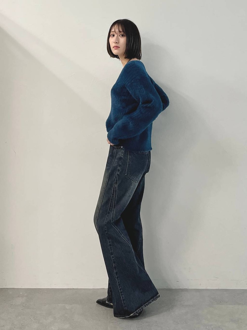 ブルー系のデニムパンツ、ブラック系のパンプス、グリーン系のニット/セーターを着用したレディースの秋コーディネートの4枚目の写真