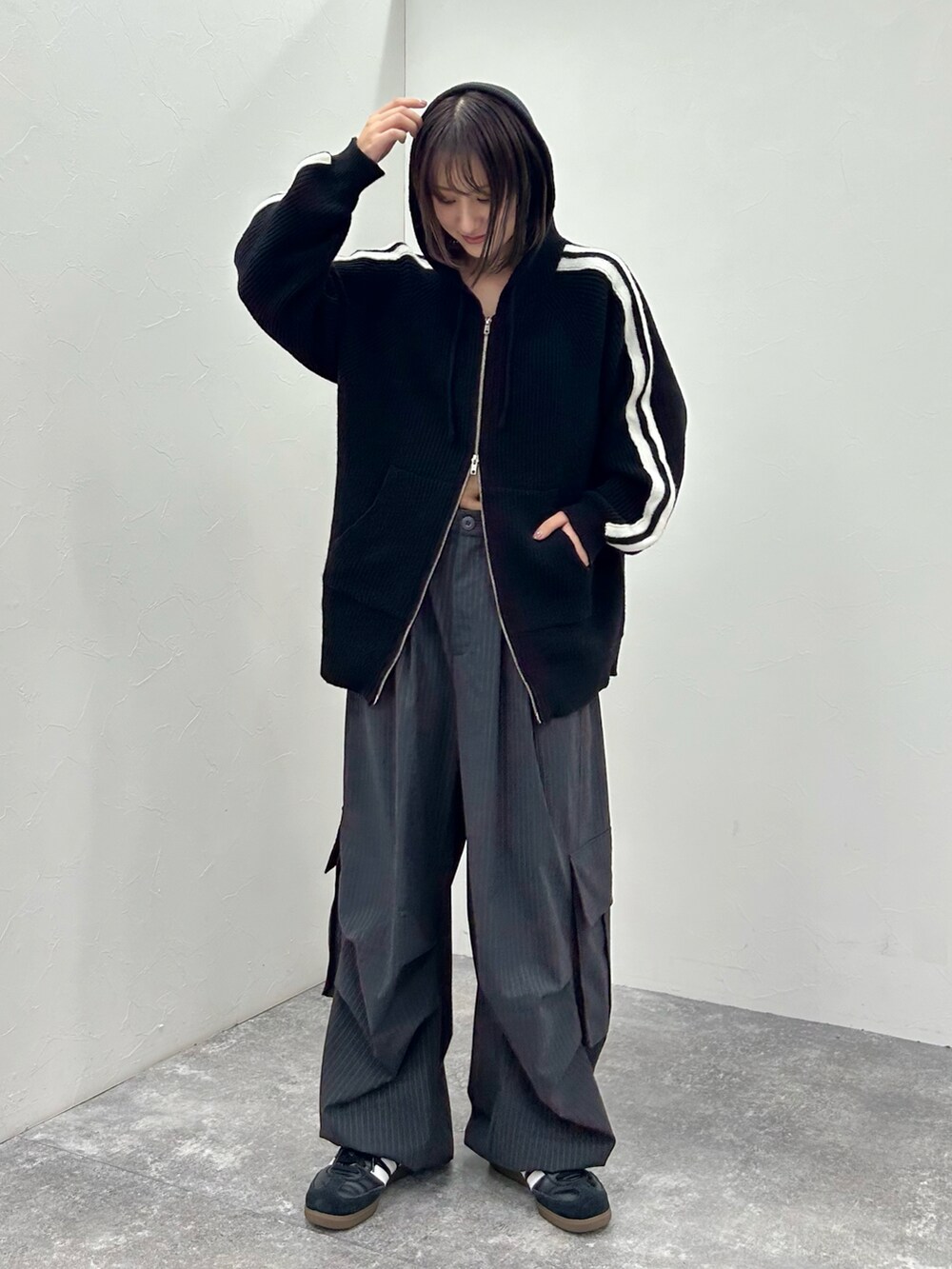 ブラック系のスニーカー、ブラック系のニット/セーター、ブラック系のカーゴパンツを着用したレディースの秋コーディネートの2枚目の写真