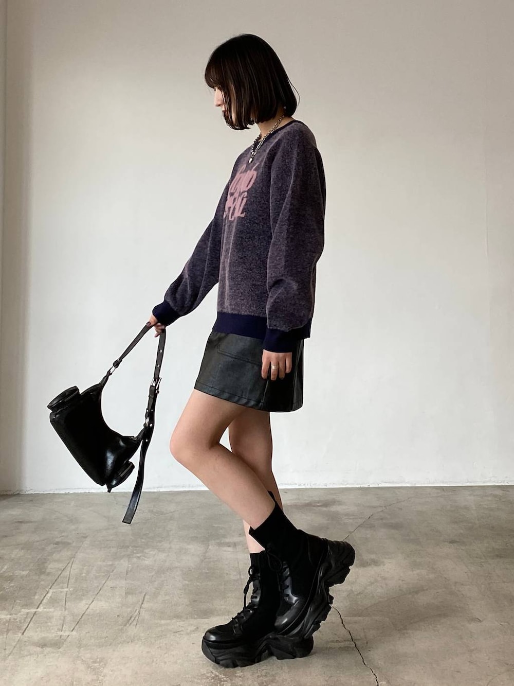 ブラック系のブーツ、ブラック系のスカート、ブラック系のショルダーバッグを着用したレディースの冬コーディネートの3枚目の写真