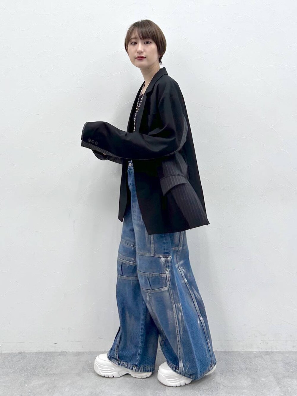 ブラック系のテーラードジャケット、ブルー系のデニムパンツ、シルバー系のネックレスを着用したレディースの春コーディネートの3枚目の写真